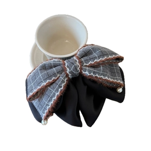 Elegant plaid hair claw with plush trim and pearl pendants on a white ceramic cup