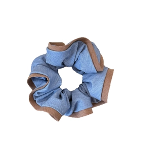 Chouchou en denim bleu avec bords à volants marrons sur fond blanc immaculé