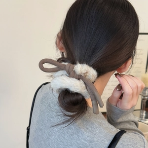 Détail d'un chouchou en peluche avec nœud porté en queue de cheval basse pour un look hiver