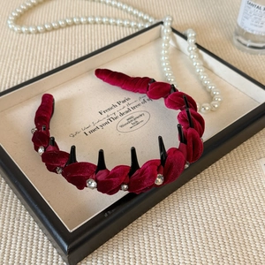 Detail of burgundy velvet braided headband with rhinestones on a display tray