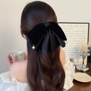 Detail of elegant black velvet bow hair clip with hanging pearl accents on back of hair
