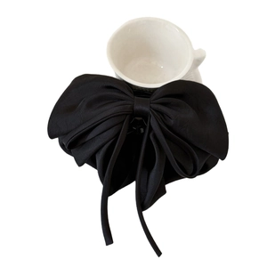 Elegant black oversized satin ribbon bow hair claw clip with long tassels on white surface