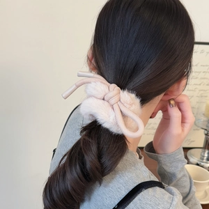 Gros plan d'un chouchou rose en peluche avec nœud montrant la texture douce de la fourrure
