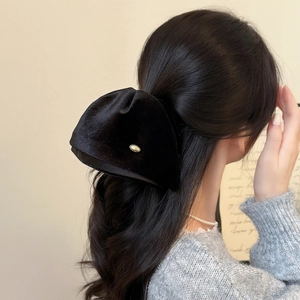 Close-up of elegant black velvet hair claw clip with golden metal logo for women