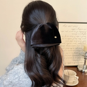 Elegant black velvet bow hair claw clip with gold button on long wavy hair