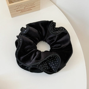 Detailed macro view of black velvet scrunchie with white floral print and ruffles