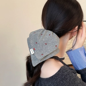 Gray knitted bow scrunchie with red cherry pattern and hand made label on low ponytail
