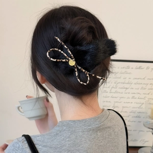 Close-up of black plush hair clip with leopard bow and gold emblem on hair
