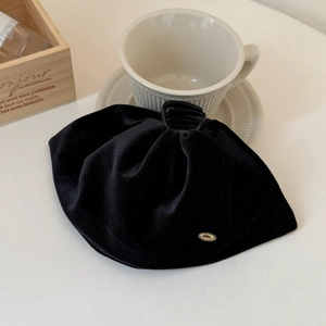 Detail of elegant black velvet bow hair claw with a gold oval metal logo tag