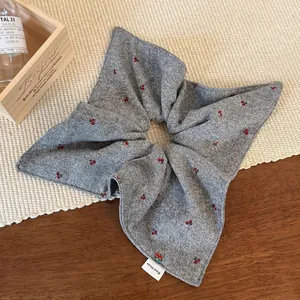 Elegant grey knitted cherry hair scrunchie with Hand Made label on wooden tabletop