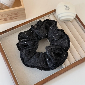 Macro shot of black polka dot scrunchie with pleated edges on a wooden tray