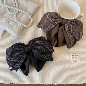Elegant floral cashew bow hair claws in black and coffee with pearl drops on woven mat