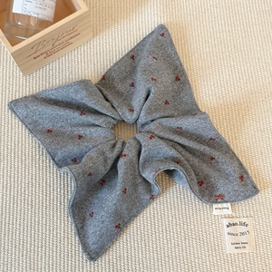 Close-up of grey knitted scrunchie with red cherry embroidery and Hand Made label