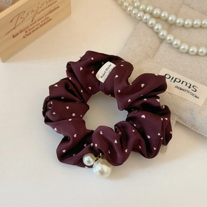 Close-up of red polka dot scrunchie with white pearl charms and handmade label