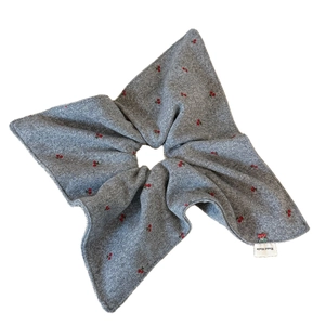 Gray knitted scrunchie with red cherry embroidery and Hand Made label on white background