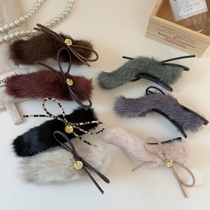 Close-up of velvet bow hair clips in various colors with golden metal branding tags