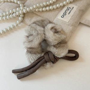 Détail d'un chouchou en peluche avec nœud en cordon brun et texture douce