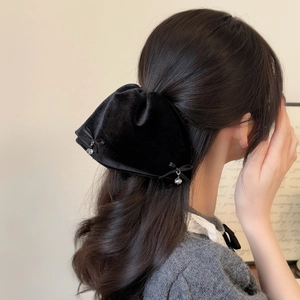 Close-up of black velvet bow hair clip with crystal pendants on female model side view