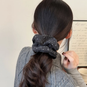 Knitted grey hair scrunchie with white polka dots shown on a low ponytail