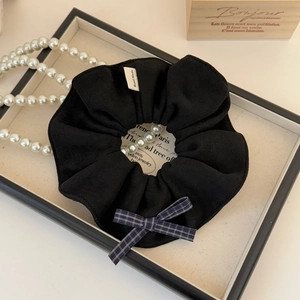 Détail d'un chouchou noir fait main avec un nœud à carreaux bleus sur un plateau chic