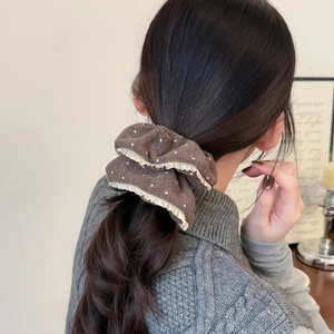 Brown polka dot scrunchie with yellow ruffled lace trim on a low ponytail