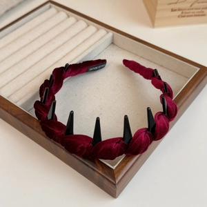 Macro detail of wine red velvet braided headband with non-slip inner teeth in a wood box