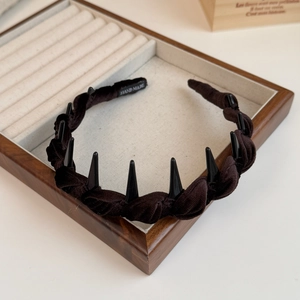 Detail of dark velvet braided headband with punk spikes and handmade label on wooden tray