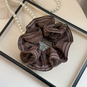 Vintage dark brown scrunchie with white geometric patterns in a luxury display box