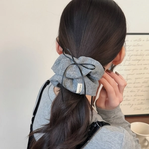 Detail of grey knitted hair scrunchie with black lace bow and Hand Made tag on hair