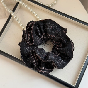 Detailed view of a vintage paisley print scrunchie in a jewelry tray with pearls