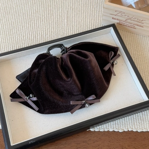 Detail of dark brown velvet bow hair claw clip with delicate beads on display tray