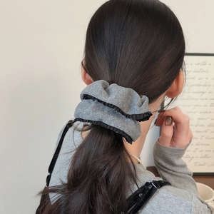 Elegant grey shimmering knit scrunchie with black lace trim on a stylish ponytail