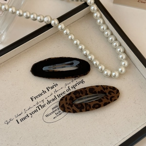 Dettaglio di fermagli per capelli in pelle scamosciata leopardata e velluto nero