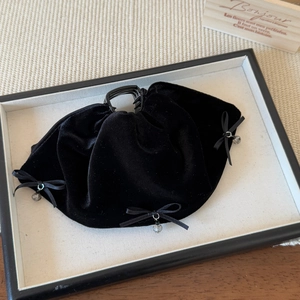Close-up of black velvet bow hair claw with transparent beads on a white tray