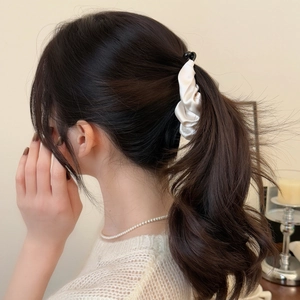 Close-up of elegant cream satin pleated banana hair clip on a curly ponytail