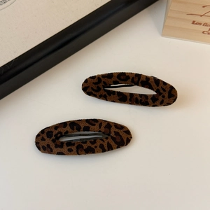 Dettaglio di due fermagli per capelli ovali con stampa leopardata e texture vellutata