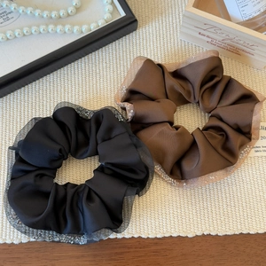 Elegant black and brown satin scrunchies with lace edges in a French vintage setting