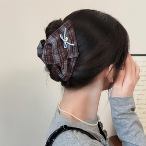 Brown plaid bow hair claw clip with gold pendant on a textured bun hairstyle