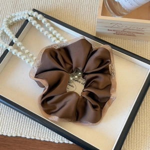 Detail of coffee brown satin scrunchie with glitter mesh edge in vintage French style