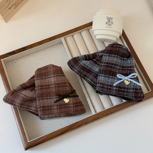 Brown and blue plaid hair clips with delicate ribbons and heart charms on a jewelry tray