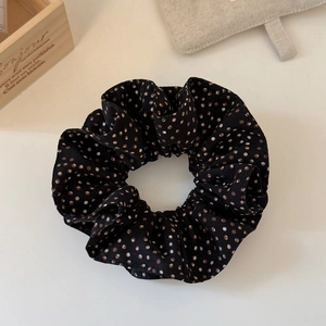 Close-up of a double-layered polka dot scrunchie on a rustic wooden box and beige bag