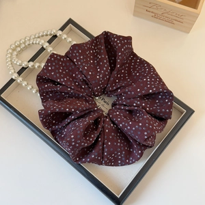 Detail of burgundy polka dot scrunchie on vintage tray with elegant french aesthetic