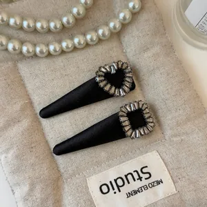 Close-up of elegant black satin hair clips with sparkling rhinestone heart and square shapes