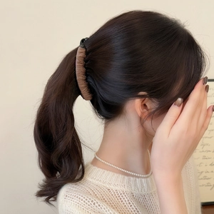 Close-up of a dark brown banana hair clip with wavy fabric texture on a ponytail