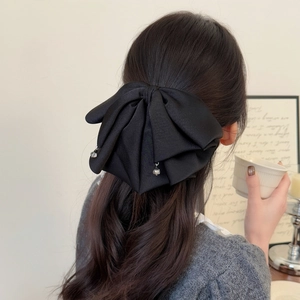 Détail d'une pince à cheveux nœud en satin noir avec pendentifs en cristal sur cheveux