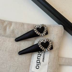 Close-up of black satin hair clips featuring a sparkling rhinestone heart decoration