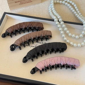 Detail view of four satin fabric wrapped banana hair clips in neutral colors on a tray