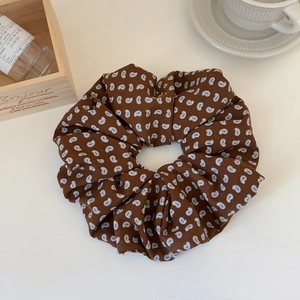 Detailed close-up of dark brown paisley print oversized fabric scrunchie on white surface