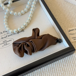 Detailed view of coffee brown pleated satin fabric on a classic banana hair clip
