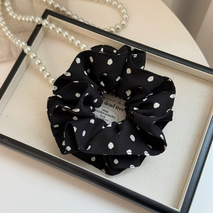 Détail d'un chouchou à pois noir avec volants et collier de perles décoratif